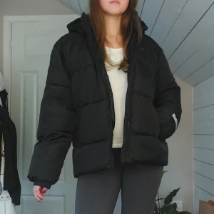 Svart pufferjacka från Lindex - Säljer en svart pufferjacka från Lindex i storlek 170. Jackan har huva, dragkedja och är tillverkad i återvunnen polyester. Lite för stor för mig som brukar ha xs-s