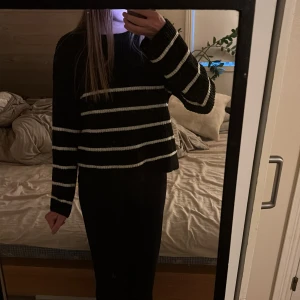 Svart stickad randig tröja - Säljer en svart stickad tröja med vita horisontella ränder. Tröjan har en loose passform och långa ärmar, perfekt för dig som gillar en avslappnad stil. Superenkel att matcha med både jeans och kjol.