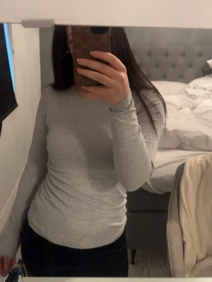 Ljusgrå långärmad topp - En ljusgrå tajt långärmad tröja, använt fåtal gånger