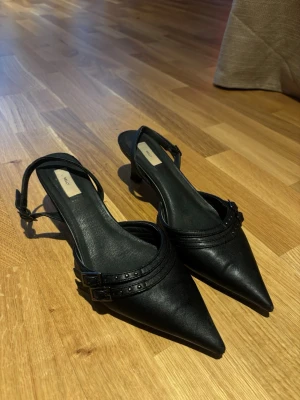 Klackar från Nelly - Låga klackar med slingback från Nelly. Fint skick men lite utnötta längst fram på tå spetsen. Upplevs lite små i storlek jag har normalt 39 i skor 