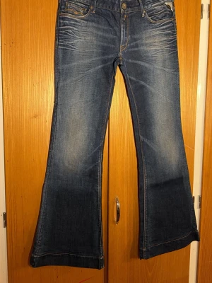 Blå Replay flare jeans, stl 31 - Säljer ett par snygga blå jeans från Replay i modellen Flare. Jeansen har klassisk femficksdesign, orangea sömmar och utställda ben. Materialet är jeans med en schysst tvättad look och coola detaljer på bakfickorna.