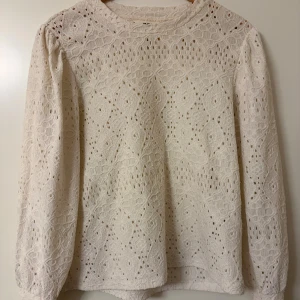 Vit blus - Vacker cremevit/vit i spetsliknande, hålmönstrad stickning 🌸 Romantisk och feminin modell med lång ärm och rak passform. Perfekt till både jeans, kjol eller över en klänning. Funkar lika bra till vardag som till finare tillfällen.