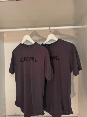 Mörkgrå t-shirt från ICANIWILL - Säljer två stycken mörkgrå t-shirt från ICANIWILL med svart logotyp framtill. Klassisk rund halsringning och korta ärmar. Perfekt för en sportig och avslappnad stil.