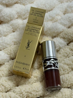 YSL Loveshine Plumping Lip Oil Gloss - YSL Loveshine Plumping Lip Oil Gloss i färgen 8 Purple Dream. Lyxig läppglansolja med plumping-effekt, kommer i en elegant guldig förpackning och har en silvrig kork med YSL-logga. Innehåller 6 ml och ger en glossig finish med en djup lila ton.