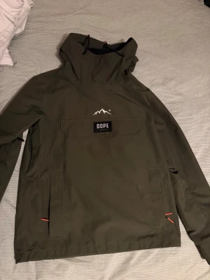 Dope Snow Blizzard - Säljer en olivgrön snowboard/skidjacka från Dope Snow modell blizzard med huva och stor magficka. Inköptes för 2-3 år sedan men råkade ut för en skada tidigt på säsongen vilket gjorde att jackan blev hängandes i garderoben. Dopes jackor är oversized vilket gör att det inte är några problem att ha lager under. Inköpspris låg på ca 2000 kr men säljer nu den för 500kr. Vid frågor eller funderingar släng iväg ett meddelande. //MB