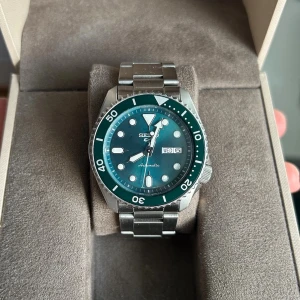 Seiko Klocka - Säljer nu en riktigt snygg original seiko klocka!  Klockan är en automatisk klocka med måttet 42 mm. Märke: Seiko. Urverk: 4R3607G0. Glas: Safir. Armband: Rostfritt stål.  Klockan är i mycket bra skick och allt fungerar som det ska. Klockboxen till vänster medföljer! Skriv till mig om ni har några funderingar, jag är även öppen för bud!