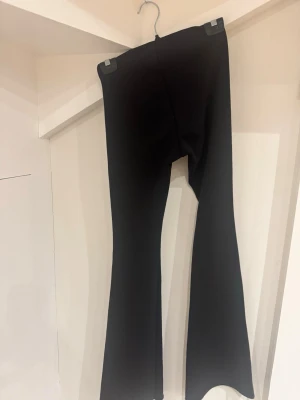 Svarta bootcut byxor med stretch - Säljer ett par svarta bootcut byxor med hög midja och stretchigt material. De har en tight passform upptill och släpper ut nedtill för en snygg siluett. Perfekta till sneakers eller boots och riktigt sköna att bära hela dagen.