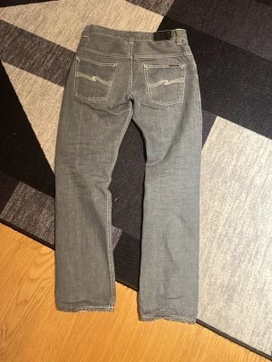 Grå jeans från Nudie Jeans Co - Säljer mina feta gråa Nudie Jeans modell even Steven Jeansen har raka ben och normal passform, samt detaljerad brodering på bakfickorna. Materialet är slitstarkt jeans i bomull.