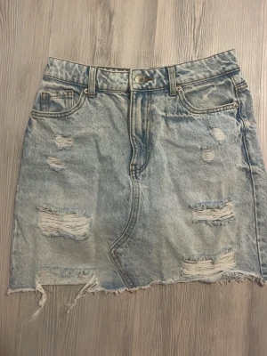 Ljusblå jeanskjol från FB Sister - Säljer en ljusblå jeanskjol från FB Sister i storlek S. Kjolen har slitna detaljer, rå kant nertill och klassiska fem fickor. Perfekt för dig som gillar en avslappnad och trendig look.