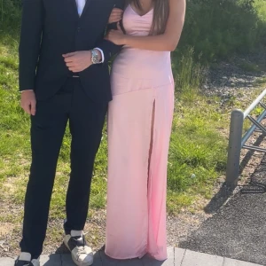Ljusrosa silkes balklänning  - Jag säljer min balklänning, ljusrosa med otrolig slits. Klänning följer kroppen perfekt och man kan justera hur löst och tajt man vill att klänningen ska sitta med hjälp av snörningen baktill, så den passar till många xxs,xs och s med mera. Perfekt till bal,bröllop och festliga sammanhang. Använd en gång och är i perfekt skick, PRIS kan diskuteras!