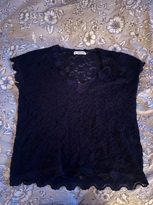 Mörkblå spetsblus med v-ringning - Säljer en jätte fin mörkblå blus i genombruten spets med blommigt mönster då den är för stor för mig💕