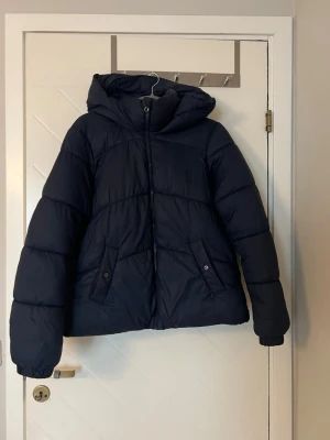 Mörkblå dunjacka  - Säljer min mörkblå dunjacka då jag köpt en annan. Jackan är mörkblå med två fickor som man kan knäppa fram. Jackan är från Vero Moda i stolen M men är liten i storleken. Jackan är varsamt använd. Nypris är 499kr men säljer för 250kr. 