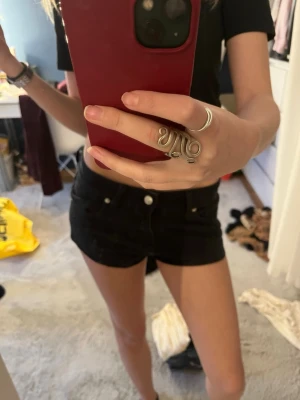 Svarta höga jeansshorts - Säljer ett par svarta höga jeansshorts med klassisk femficksdesign och knappgylf. Shortsen har en tight passform och är perfekta för sommaren. Passar till allt och är ett måste i garderoben!