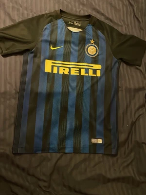 Inter Milan matchtröja Nike - Snygg Inter Milan matchtröja från Nike med klassiska blå och svarta ränder, gul Pirelli-logga och klubbmärke på bröstet. Korta ärmar och sportig passform, perfekt för fotboll, träning eller för att bara gå ut.