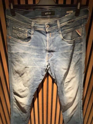 Replay ljusblå jeans herr - Ljusblå jeans från Replay med klassisk femficksdesign och diskreta slitningar. Jeansen har raka ben och detaljerade sömmar på bakfickorna. Tillverkade i denim med en något tvättad look och orangea sömmar.