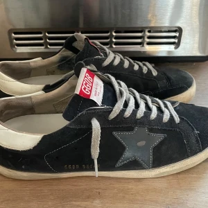 Svarta/blåa sneakers från Golden Goose - Snygga svarta sneakers från Golden Goose. Nypris runt 6000! Skorna är 7 av 10 skick då hälen blivit lagad .