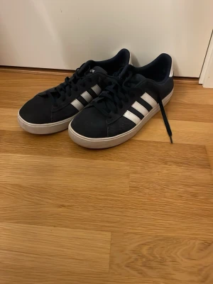 Marinblå Adidas sneakers med vita ränder - Skorna är använda men fortfarande i mycket bra skick utan defekter. 