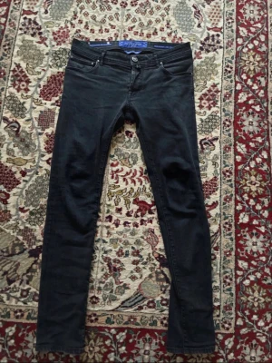 Jacob cohën jeans - Svarta skinny jeans från Jacob cohën med klassisk femficksdesign och knappgylf. Jeansen har en smal passform och är tillverkade i stretchigt jeanstyg för extra komfort. Perfekta för en stilren och modern look.