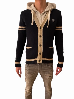 Marinblå stickad kofta från JP - Säljer en marinblå stickad kofta från JP med beige detaljer och knappar framtill. Koftan har två fickor, ribbade muddar och beige ränder på ärmar och nederkant. Klassisk badge på bröstet och normal passform. Perfekt för lager på lager under höst och vinter.