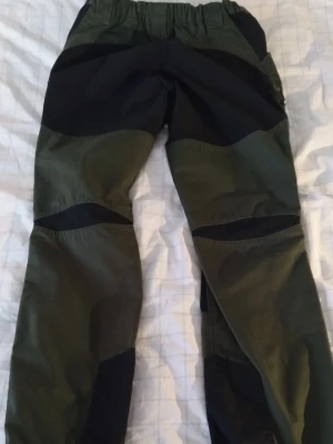 Gröna cargopants med svarta detaljer - Säljer ett par gröna pants med svarta förstärkningar på knän och ben. Byxorna har flera fickor och en cool outdoor-look. Perfekta för dig som gillar funktionella och snygga byxor. Märke: RVRC
