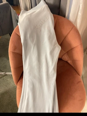 Ljusgrå mjukisbyxor Juicy Couture - Supermjuka ljusgrå mjukisbyxor från Juicy Couture med broderad logga framtill och diskreta fickor. Klassisk relaxed fit och bred resår i midjan för extra komfort. Perfekta för chill dagar eller när du vill vara extra bekväm.