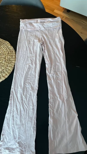 Ljusrosa yogapants från Gina Tricot - Supersköna ljusrosa leggings från Gina Tricot med utsvängda ben och bred linning. Tillverkade i mjukt bomullsmaterial som känns bekvämt hela dagen. Perfekta för dig som gillar en avslappnad och trendig stil.