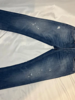 Dondup Jeans - Tja säljer ett par Dondup George jeans. Trendigaste jeansen på marknaden. Vårt pris är 899kr medans nypriset ligger på 4000kr. Jeansen är i fint skick och har original slitningar från fabrik vilket är mycket eftertraktat och populärt. Skriv vid frågor eller ifall du vill ha fler bilder.