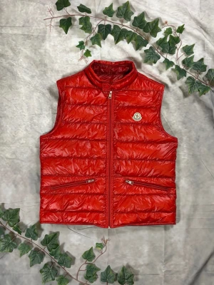 Moncler Gui Down Vest – Röd – Strl 3 (M) - |Färg: Röd, blank nylon | Modell: Gui Down Vest, lättviktsdun | Storlek: 3 (M), normal passform | Skick: Grade A, 10/10 | Hör av dig ifall du har funderingar!