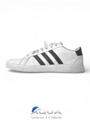 Vita Adidas sneakers med svarta ränder - Klassiska vita sneakers från Adidas med de ikoniska tre svarta ränderna på sidan. Skorna har snörning, rund tå och platt sula. Perfekta för en stilren och sportig look. Tillverkade i syntetmaterial och textil.