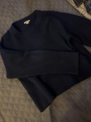 Mörkblå stickad tröja med loose fit - Mysig mörkblå stickad tröja med rund halsringning och långa ärmar. Tröjan har en loose fit och ribbade muddar vid ärmslut och nederkant. Perfekt till chill outfits med jeans, kjol, shorts eller bara mjukisbyxor