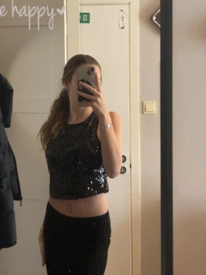 Svart paljett-crop top - Snygg festlig svart croppad topp täckt med glittriga paljetter. Toppen är ärmlös och har en rund halsringning, perfekt för att sticka ut. Endast provat en fåtal gånger!