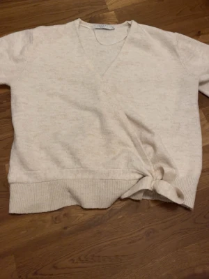Beige stickad tröja från Costes - Snygg beige stickad tröja från Costes med v-ringning och knytband i sidan. Pris går att diksuters, hör av er vid frågor, storlek S 