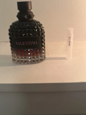 Valentino parfym born in Roma intense  - Säljer en lyxig parfym från Valentino i en cool flaska med nitar och svart lock. Flaskan har en snygg övergång från svart till transparent med röd toning. Perfekt för dig som gillar exklusiva dofter och snygg design.