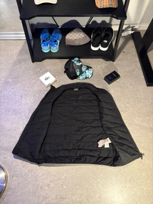 Svart dunjacka från EA7 Emporio Armani - Snygg svart dunjacka från EA7 Emporio Armani med quiltad design och diskret logga på bröstet. Jackan har dragkedja och är perfekt för kyliga dagar. Stilren och lätt att matcha med olika outfits.