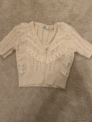 Stickad cardigan från Zara  - Supersöt beige stickad kofta från Zara med spetsdetaljer och knappar framtill!