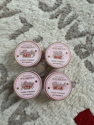 Plouise lösa pigment - 4 färger - Fyra burkar lösa pigment från Plouise i nyanserna Slumber Party, Wide Awake, Starry Stop och Dusted Dreams. Förpackningarna är runda och rosa med lock i plast. Perfekt för att skapa kreativa och färgstarka ögonmakeuper med intensivt skimmer.