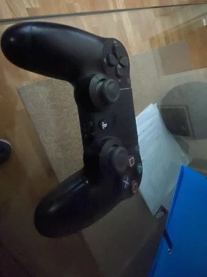 PlayStation DualShock 4 Wireless Controller - Snygg och ergonomisk PlayStation DualShock 4 trådlös handkontroll från Sony. Svart färg, alla knappar och styrspakar syns i gott skick. Perfekt för spel på PlayStation 4. Inga synliga defekter eller större slitage på ytan.