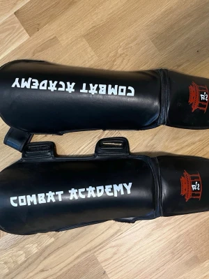 Svarta benskydd kickboxning - Säljer ett par nya svarta benskydd för thai/kickboxing. De var kardborrband för flexibel storlek.