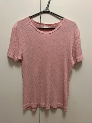 Ljusrosa ribbad topp i 100% bomull strl 50/52 - Ljusrosa ribbad topp i 100% bomull med korta ärmar och rund hals. I mycket bra skick. Storlek 50/52.