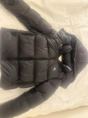Svart pufferjacka från Calvin Klein Jeans - Svart pufferjacka från Calvin Klein Jeans med huva och dragkedja. köpte den förra året den är mycket bra skick. skriv vid frågor 🤗