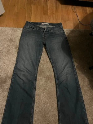 Levi's 512 Bootcut jeans mörkblå - Säljer ett par Levi's 512 Bootcut jeans i mörkblå tvätt. Klassisk femficksmodell med låg midja och bootcut-ben. Jeansen har slitningar och snygga detaljer vid bensluten. Perfekt för dig som gillar en avslappnad och tidlös stil.