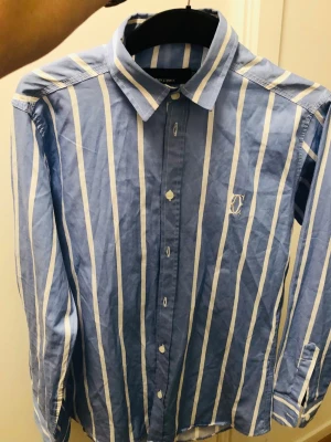 Blåvit randig skjorta från Only & Sons plus en sweatshirt  Lyle@Scott - Snygg skjorta i blått med vita vertikala ränder från Only & Sons. Klassisk krage, långa ärmar och knappar framtill. Broderad logga på bröstet. Perfekt för dig som gillar stilrena och fräscha plagg med lite edge. Plus en sweatshirt mörk blått från Lyle& Scott.