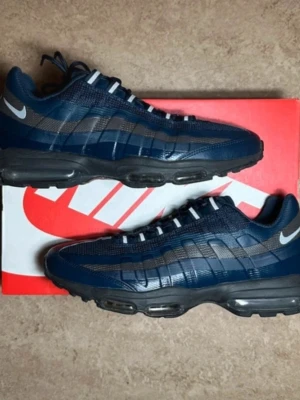 Nike Air Max 95 ultras marinblå sneakers - Hwlt nya Nike Air Max 95 sneakers i marinblått med svarta och grå detaljer. Skorna har synlig Air Max-dämpning i sulan, snörning med vita öglor och en rund tå. Ovandelen är i syntet och mesh för bra ventilation. Swoosh-logga i silver på hälen.