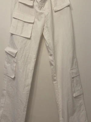 Vita cargopants från LeGer - Säljer ett par vita cargopants från LeGer. Har inte använt de alls alltså helt nya fast utan prislapp använt med flera stora fickor på benen. Byxorna har en loose passform och är tillverkade i bomull. Perfekta för dig som gillar streetstyle och vill ha mycket plats för prylar.