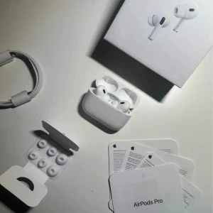AirPods Pro - Apple AirPods Pro trådlösa hörlurar med laddningsetui, extra öronkuddar och originalförpackning. Komplett med laddningskabel och manualer. Produkten ser ut att vara i mycket gott skick utan synligt slitage eller defekter. Perfekt för brusreducering och hög ljudkvalitet.