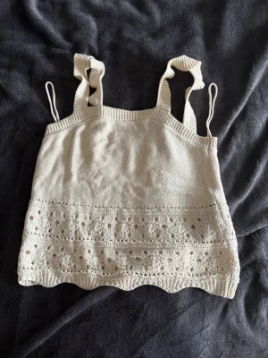 Sommar topp  - Säljer en beige stickad linnetopp med breda axelband och spetsdetalj där nere. Använd några gåmger så den är i bra skick!