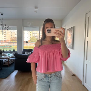 Rosa offshoulder topp - En söt rosa offshoulder topp med puffiga korta ärmar. Toppen har smock upptill som håller den på plats och ger en snygg volangig effekt. Står storlek S men skulle säga att den även passar XS. Har ett litet hål framtill.❤️