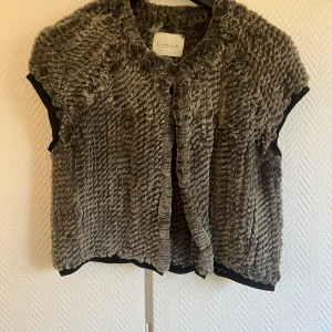 Kaninpäls från Rosemunde - Säljer en fluffig och lyxig grå pälsväst från Rosemunde. Västen är tillverkad i 100% kaninpäls i absolut högsta kvalitet. Kort passform.