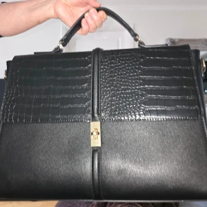 Svart väska från Anna Field - Stilren svart väska från Anna Field med snygga krokopräglade detaljer på framsidan och guldfärgat lås. Väskan har ett stadigt handtag och är tillverkad i syntetmaterial. 