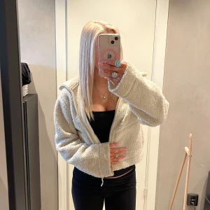 Beige teddyjacka med dragkedja - Mysig beige teddyjacka med croppad passform och bred krage. Jackan har en hel dragkedja framtill och är tillverkad i fluffigt fleece-material som ger en chill och trendig vibe. Perfekt för att hålla sig varm och se snygg ut under höst och vinter. Har en liten fläck på innersidan men abslout inget man tänker på. Skriv innan köp! Och frågor ❤️❤️